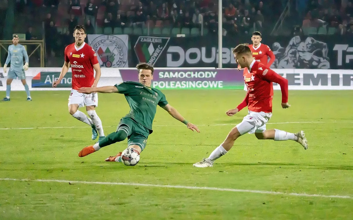 Gece maçında rakip baskısı altında top süren futbolcu