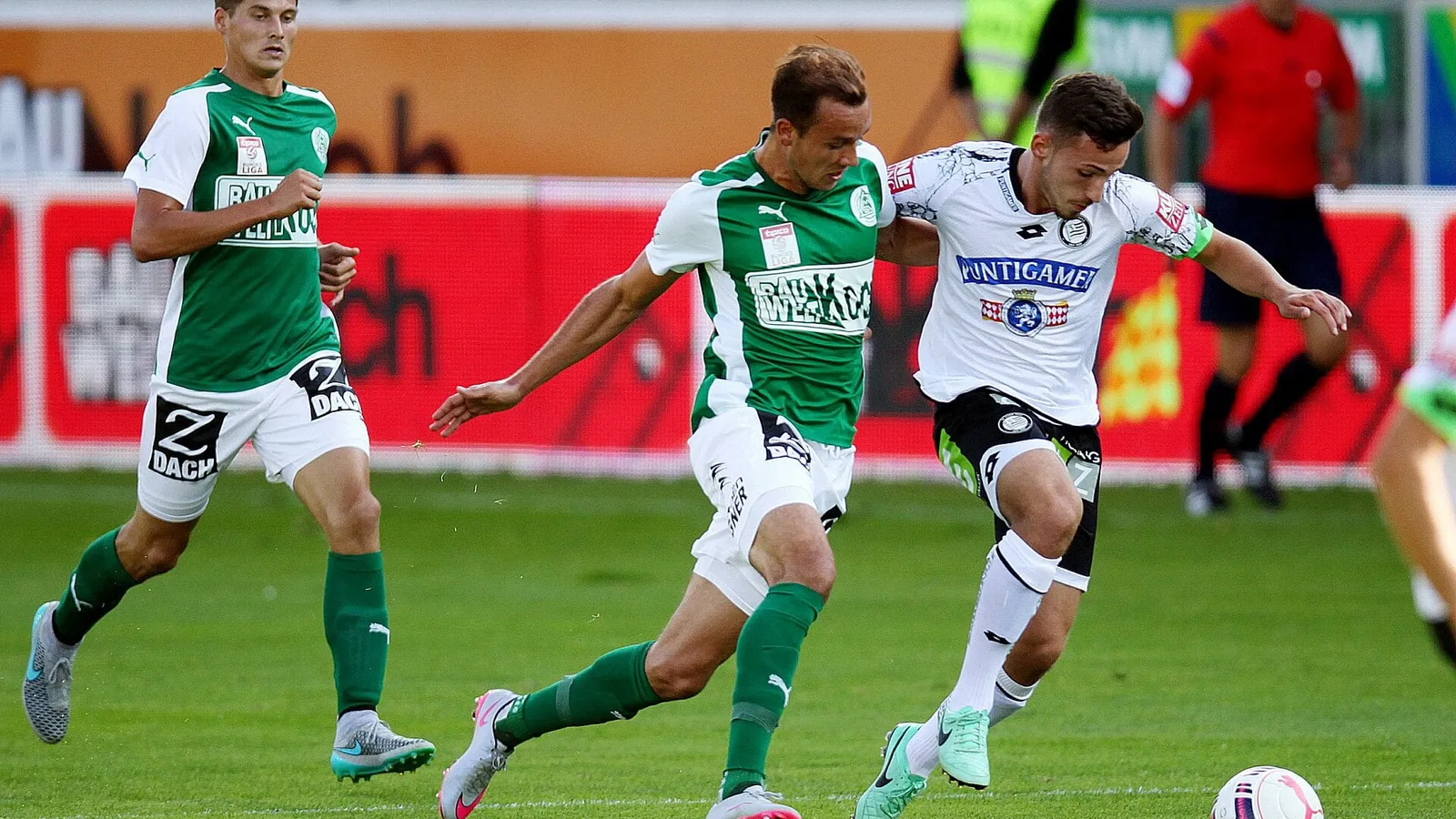 Yeşil ve beyaz formalı futbolcular top için koşuyor