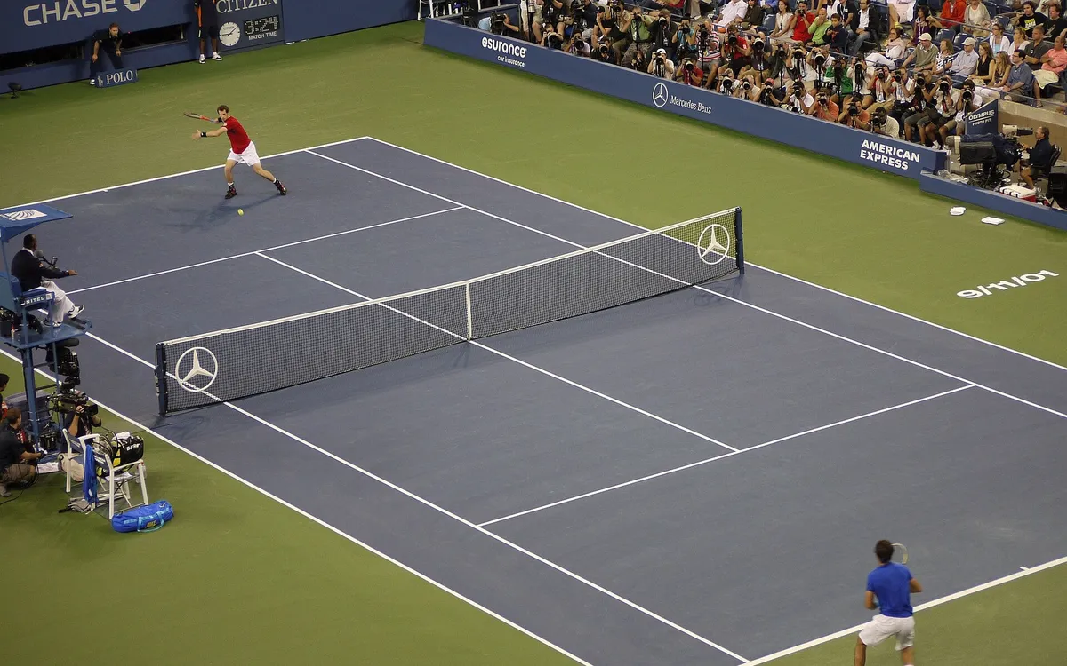 Kalabalık bir stadyumda sert kortta oynanan tenis maçı